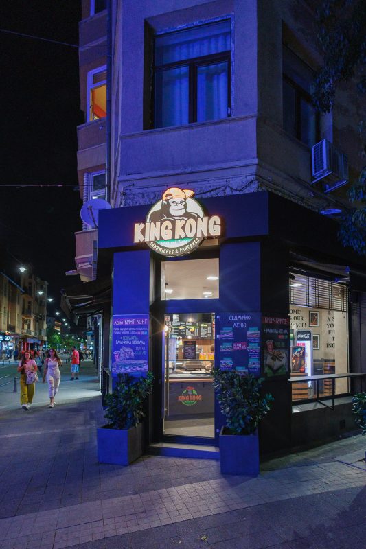 King Kong sandwiches and pancakes shop with illuminated sign and storefront at night on a pedestrian street in Sofia, Bulgaria