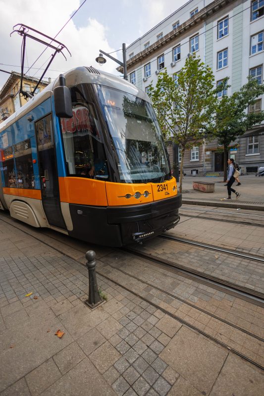 Modern orange and white tram number 2341 at a stop in central Sofia with neoclassical buildings in background, Bulgaria