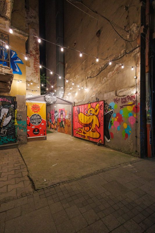 Colorful street art and graffiti murals illuminated by string lights in the Urbean Garden alleyway at night, Sofia, Bulgaria