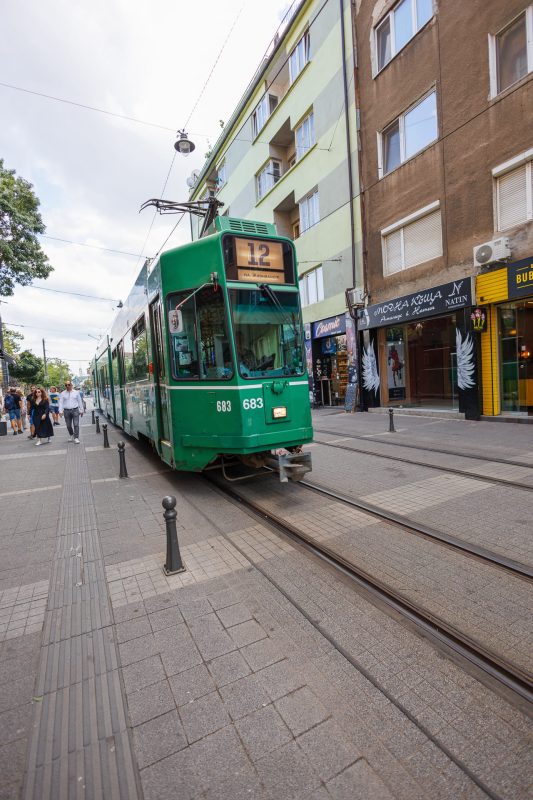 Vintage green tram number 683 on line 12 traveling through a commercial street in Sofia, Bulgaria, with pedestrians and shops visible