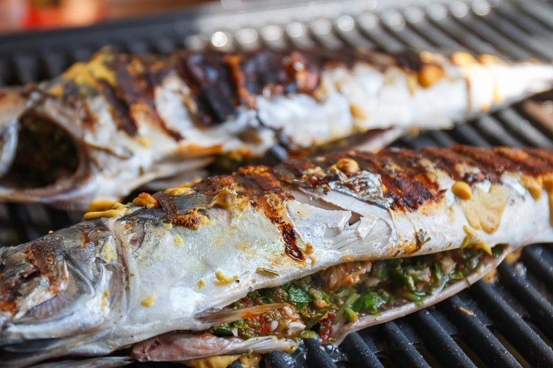 Whole fish stuffed with fresh herbs grilling on a barbecue